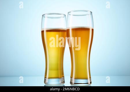 Fizzy yellow beer poured to tall glasses on light blue. Stock Photo