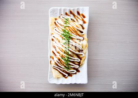 Japanese rice omelette stuffed with vegetables, meat and covered with various sauces. Stock Photo