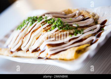 Japanese rice omelette stuffed with vegetables, meat and covered with various sauces. Stock Photo