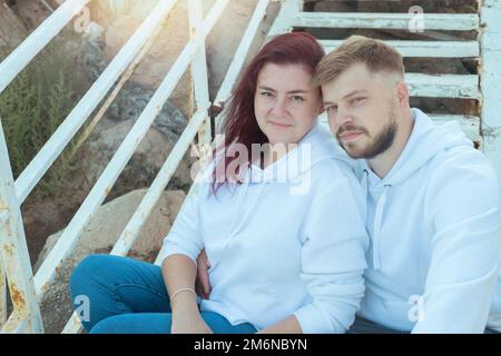 Young beautiful mixed race couple is sitting on the stairs and hugging. Stock Photo