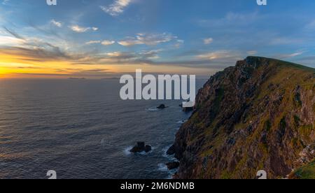 Sunset over the Atlantic Ocean and the cliffs of Bray Head on Valentia Island in County Kerry of western Ireland Stock Photo