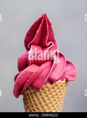 A waffle ice cream cone filled with a delicious freshly made raspberry soft serve ice cream. Stock Photo