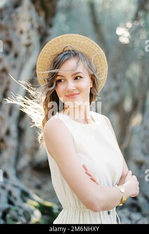 Smiling woman in a straw hat crossed her arms over her chest Stock Photo