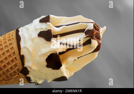 A close up of an ice cream cone with vanilla ice cream and chocolate icing. Stock Photo