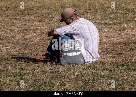 Man sitting on grass wearing a felt hat Stock Photo