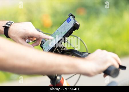 Man planning route using GPS navigation application in mobile phone on his bicycle bike. Stock Photo