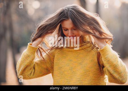 Young woman model in autumn park with yellow foliage maple leaves. Fall season fashion. Stock Photo