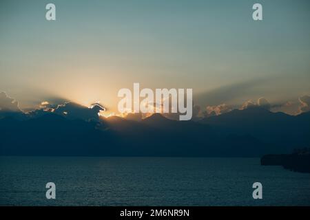 Dramatic sunset rays through cloudy dark sky over the ocean Stock Photo
