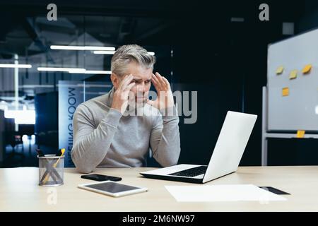 Senior thinking businessman working inside office with laptops, man thinking about important financial decision. Stock Photo
