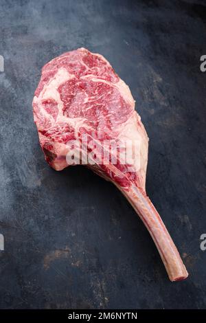 Raw dry aged wagyu tomahawk steak offered as top view on an old black rustic board with copy space Stock Photo