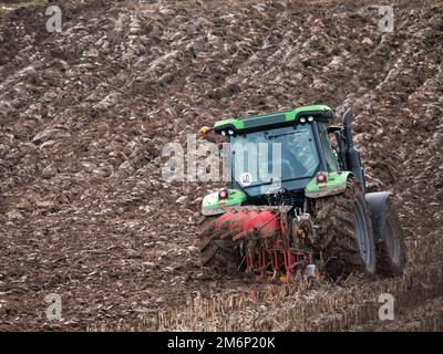 Farm tractor furrowing corn field in late autumn Stock Photo