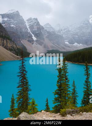 Lake moraine during a cold snowy day in Canada, turquoise waters of the Moraine lake with snow Stock Photo