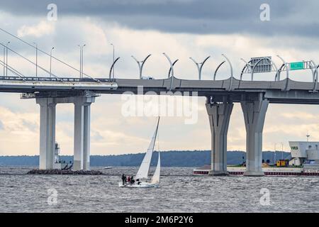 Russia, St. Petersburg, 29 July 2022: Small sport sailing yacht at stormy weather, highly cable-stayed bridge on background Stock Photo