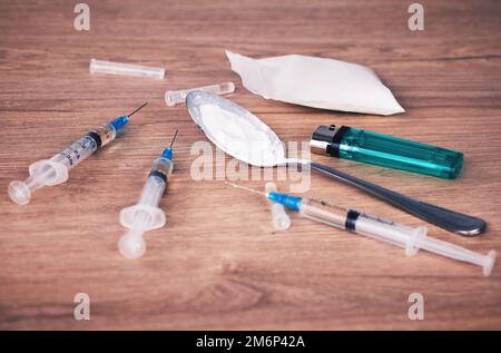 Powder, syringe and drugs with spoon on table for alcohol addiction, drug rehabilitation and narcotics abuse. Medicine, illegal drug and addict Stock Photo