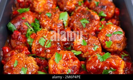 Homemade meatballs with tomato sauce, spices and fresh green parsley in black pan close up. Tasty cooked meat balls made with minced beef. Top View, F Stock Photo