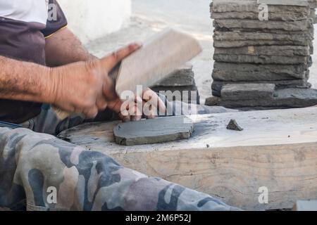 Worker manually forming a clay tile in potter factory in Fez, Morocco, North Africa Stock Photo