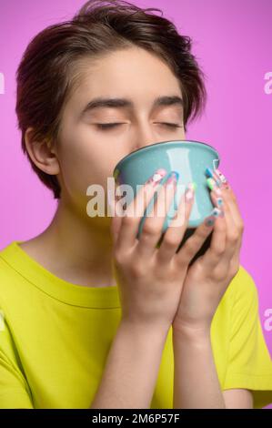 Bored young girl drinking from big cup of tea or coffee at morning Stock Photo