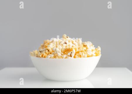 Tasty cheese popcorn in bowl isolated on white background close up. Movies, cinema and entertainment concept. Stock Photo