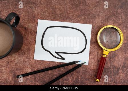 Thought Bubble Drawing On Paper With Coffee Mug, Colored Pencils And Magnifying Glass Placed On Wood. It Is Representing Researc Stock Photo