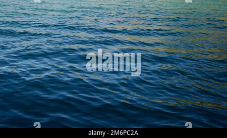 Waveless, calm sea at sunset. Pale sun rays reflecting off the sea. Stock Photo