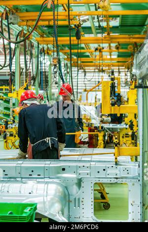 Two workers at a truck factory in Asia. Stock Photo