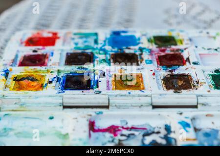 used and stained watercolor paints with blurred background and copy space, on a table outdoors. Stock Photo