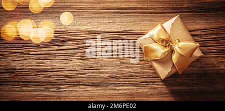 Kraft paper gift box with gold ribbon bow on old wood texture Stock Photo