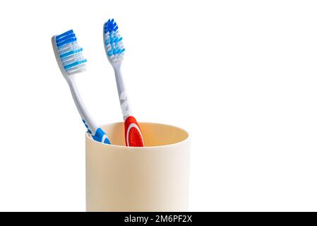 View of new toothbrush red and blue handle in plastic cup isolated on white background. Stock Photo