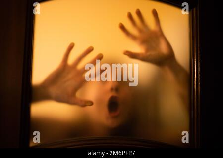 Scary picture of hands behind glass, horror ghost woman behind door, Halloween  concept Stock Photo