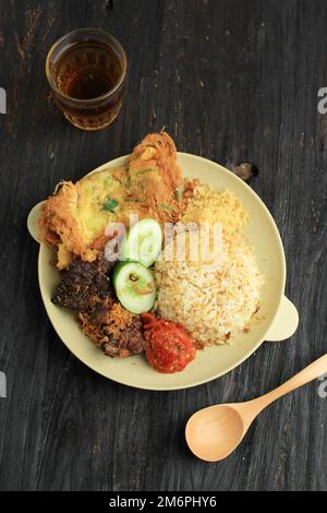 Sego Buk or Nasi Campur Madura, Indonesian Traditional Mixed Rice with Cow Lung, Sambal, and Egg. Top View, Served with Tea Stock Photo