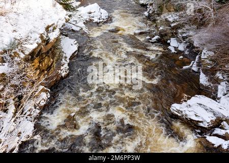 Braemar Scotland looking down Clunie Water from the bridge and the river banks covered by snow in winter Stock Photo