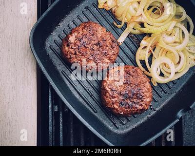 Cooking minced beef burger on cast iron grill skillet outdoors, red meat on frying pan, grilling food in the garden, English cou Stock Photo