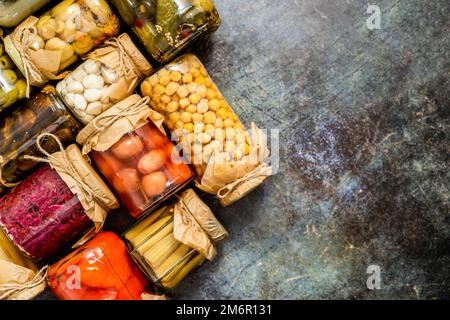Various kinds preserves vegetables and mushrooms in glass jars. Stock Photo