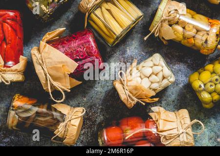 Closed pickling jars with various vegetables on stone table Stock Photo