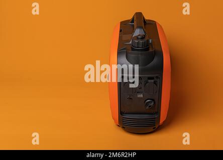 Inverter gasoline generator on an orange background. Stock Photo