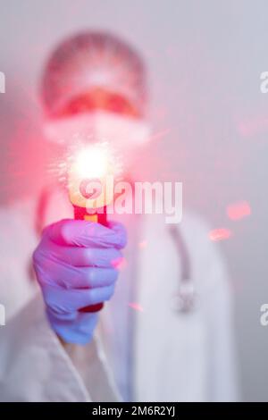 Healthcare worker holding gun thermometer and wearing coronavirus covid19 mask Stock Photo