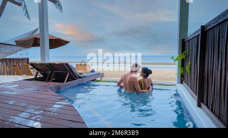 Couple in luxury villa enjoying in the plunge pool looking out over ocean and beach during sunset Stock Photo