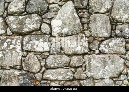 A background of an old stone wall built with uneven and random blocks and stones Stock Photo