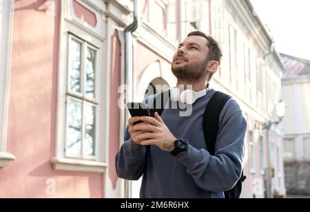 Adult man tourist walking around city searching historical places using his smart phone for navigation. Stock Photo