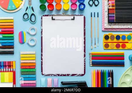 Colorful school supplies placed on blue background with white plain paper in the middle Stock Photo