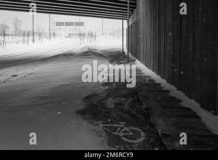 Bike path under the snow. Close-up of snow on the road. Impossible to take a bike. Snow storm. Road covered with snow in the middle of a storm. Stock Photo