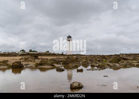 The historic Southerness Lighthouse in Scotland with reflections in tidal pools in the foreground Stock Photo