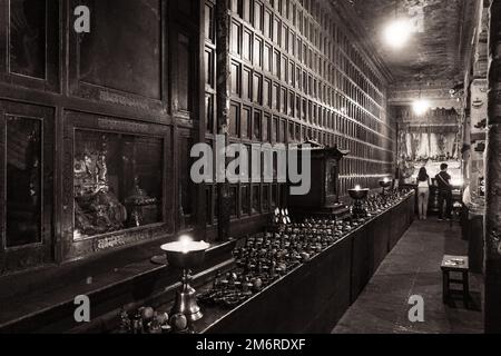 Candles and offerings on a decorated wall of cabinets and figurines, Kumbum Monastery, Xining, China Stock Photo