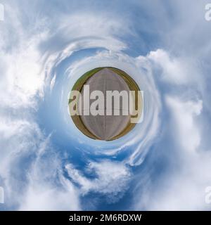 tiny planet in blue overcast sky with beautiful clouds with transformation of spherical panorama 360 degrees. Spherical abstract aerial view. Curvatur Stock Photo