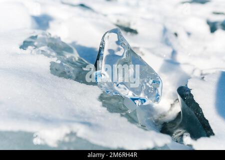 Pieces of ice lying on the ideal smooth ice of baikal with ice hummocks in the horizon Stock Photo