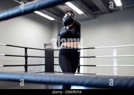 Strong latin boxing woman on the ring at fitness gym. Athletic girl training Muay Thai boxing for bodybuilding and healthy lifes Stock Photo