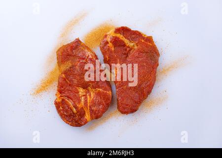 Traditional raw seasoned pork neck steak prepared for a summer barbecue and offered as top view on a white board with copy space Stock Photo