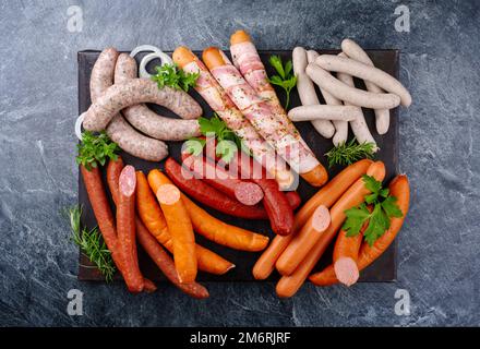 Traditional raw grill platter with different types of bratwursts prepared for a summer barbecue offered as a top view on a rusti Stock Photo