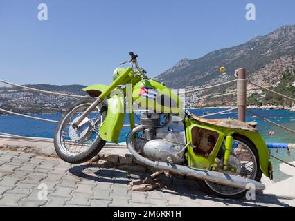 An old motorcycle sits at the entrance to the Kalkan Beach club in the town of Kalkan, Turkey. July 2022 Stock Photo