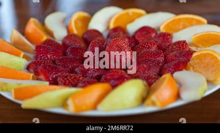 A plate of fruit, consisting of strawberries, oranges and pear, served on a charter boat day cruise from the town of Kalkan, Turkey. July 2022 Stock Photo